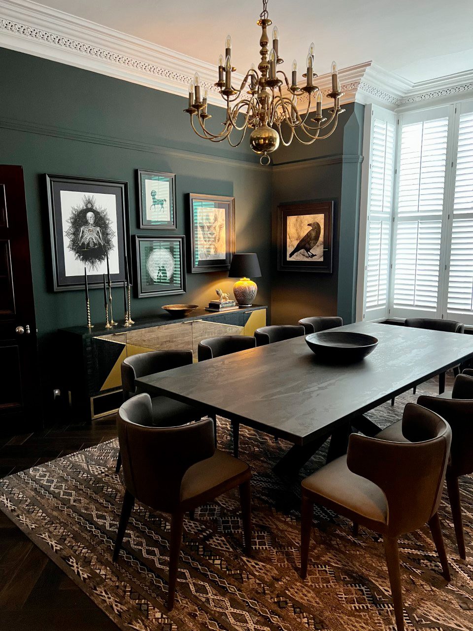 Dekton dining table with upholstered chairs in a dark green dining room